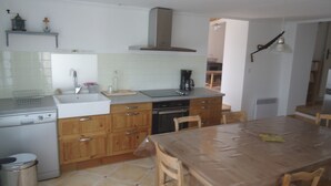 Cocina compacta con armarios de madera, un lavamanos, una estufa y una mesa de comedor con sillas.
