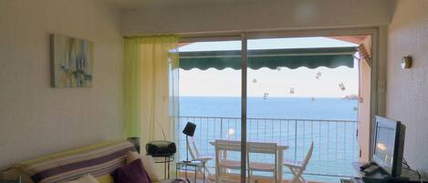 A balcony with a sofa, chairs, a small table, and a TV.