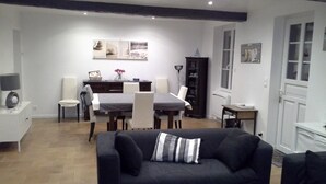 Un salon avec un canapé noir, une table à manger avec des chaises et un buffet.