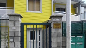 Un bâtiment jaune avec une porte bleue, une boîte aux lettres et un pilier en pierre.