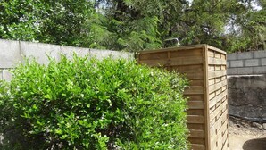 Un abri en bois, en partie dissimulé par un feuillage vert et dense.