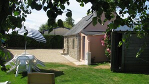 A backyard with a stone building, a covered patio area, and a small shed.