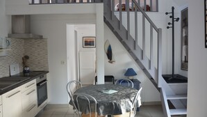 A compact kitchen with a dining area, a staircase, and a small living space.