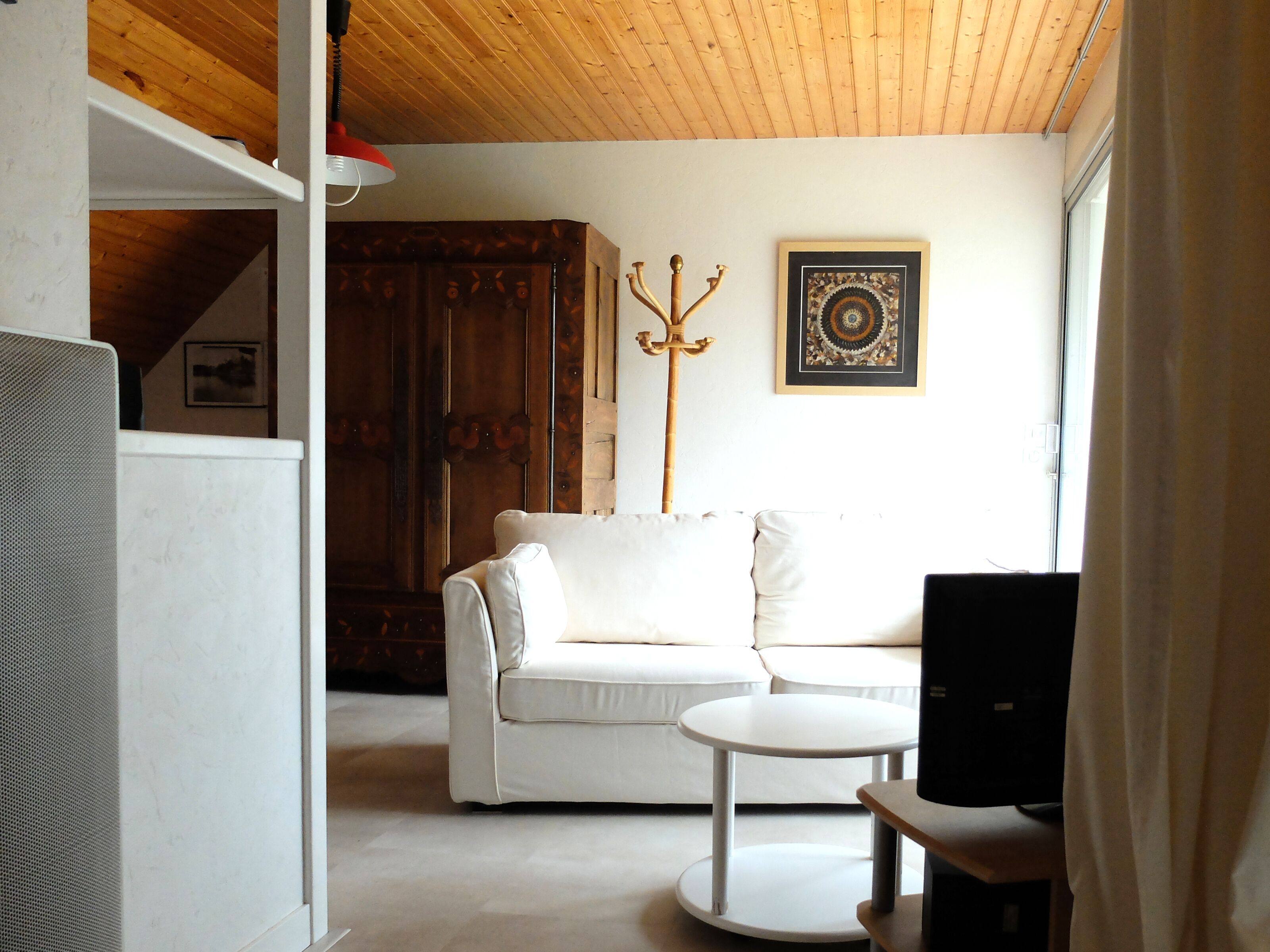 A living room with a white sofa, a small round table, and a wooden cabinet.