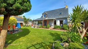A house with a well-maintained lawn, a patio with outdoor furniture, and a garden with various plants.