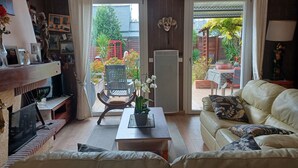 A living room with a sofa, a chair, a coffee table, a fireplace, and a view of a garden through a sliding door.