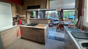 A kitchen with a central island, a dining area with a table and chairs, and a view of the outdoors.