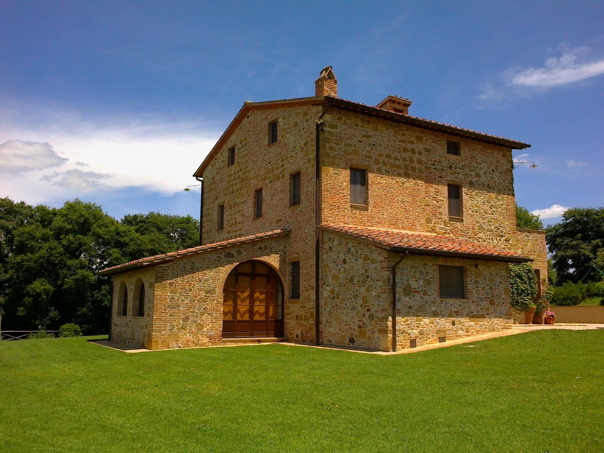 A two-story stone building with a large arched entrance and a tiled roof.