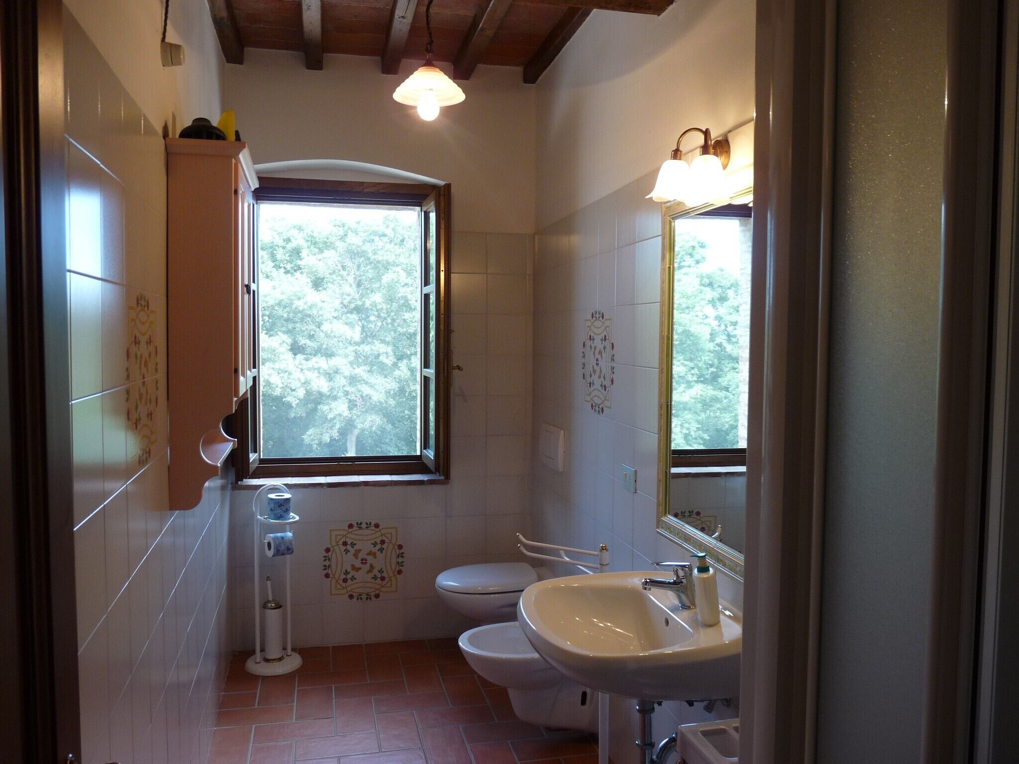 Une salle de bain avec une fenêtre, des toilettes, un lavabo et une douche.