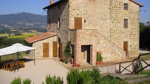 Un edificio de piedra con un patio, mobiliario exterior y vistas al campo.