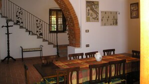 Un comedor con un arco de ladrillo, una escalera de madera y una mesa con sillas.