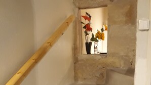 En trappe med et trægelænder, et lille vindue med blomsterudsigt, og en enkel væg.