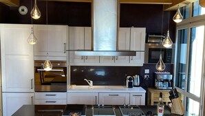 A modern kitchen with white cabinets, a central island, hanging pendant lights, and a stainless steel range hood. - Superb chalet apartment with views of the Cerdagne - 3 minutes from the cable cars (Font-Romeu-Odeillo-Via)