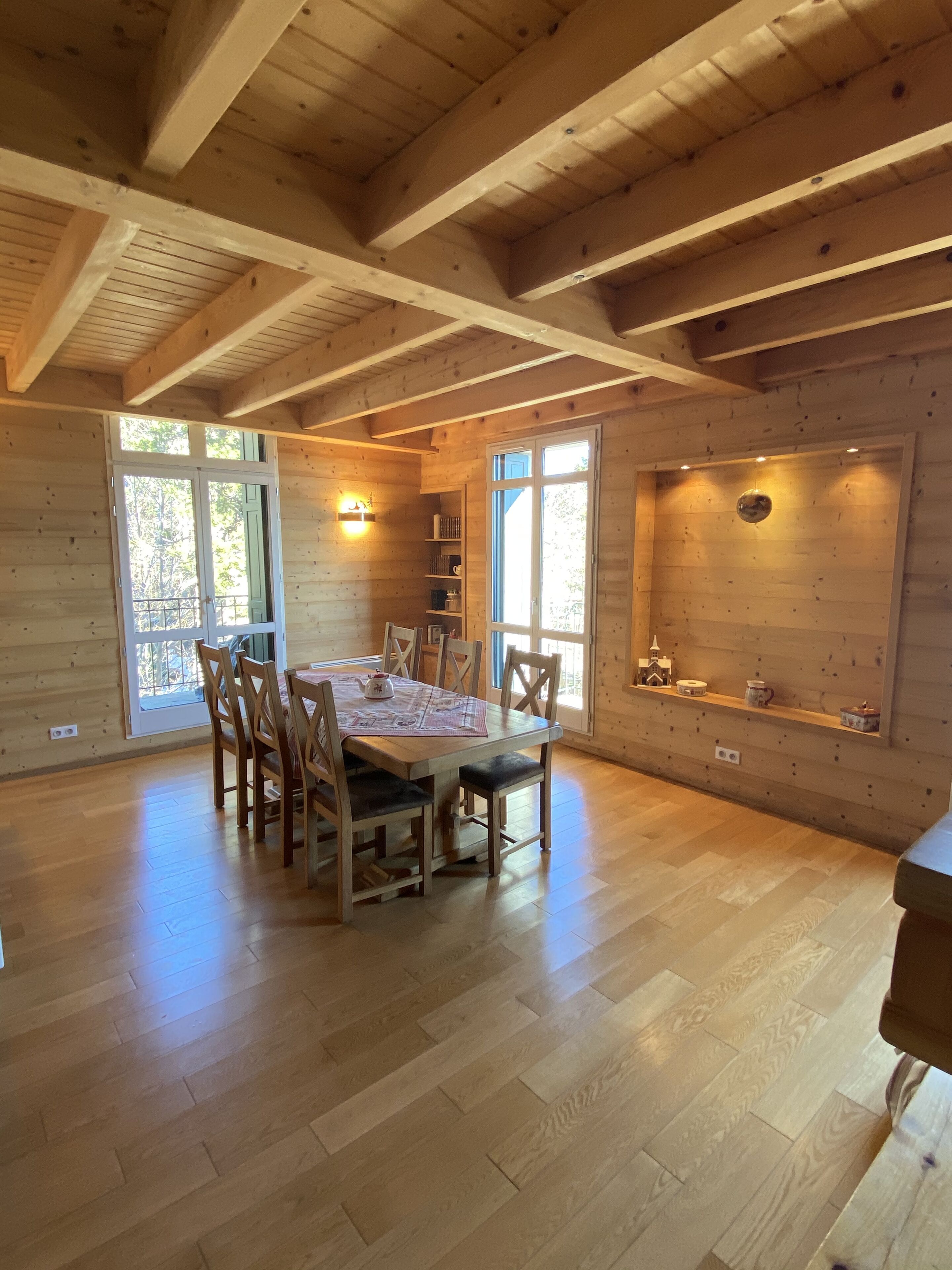 Ein Holzinterieur mit einem Esstisch, Stühlen und einem Regal mit Dekoration.