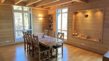 Un interior de madera con una mesa de comedor, sillas y una estantería con objetos decorativos.