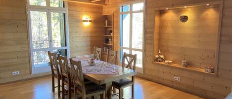 Ein Holzinterieur mit einem Esstisch, Stühlen und einem Regal mit Dekoration.