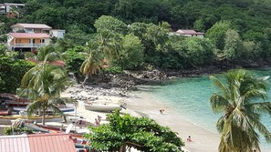 Une plage bordée d’une eau turquoise et limpide, de palmiers et d’une côte rocheuse.