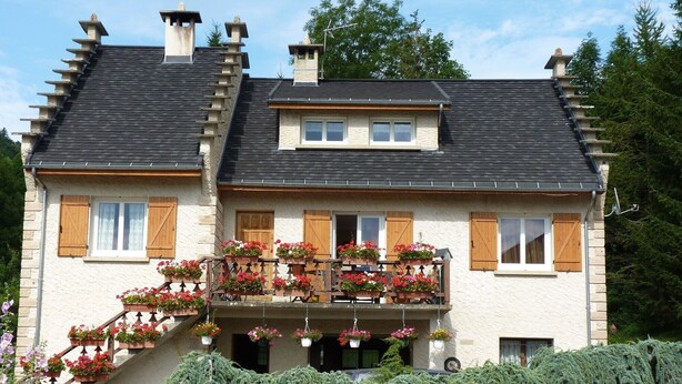 Ein zweistöckiges Haus mit einem Balkon, der mit Blumentöpfen und Blumen geschmückt ist.