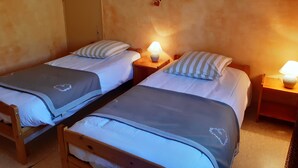 Ein Zimmer mit zwei Holzbett, jedes mit einem Kopfkissen und einem Nachttisch mit Lampe.