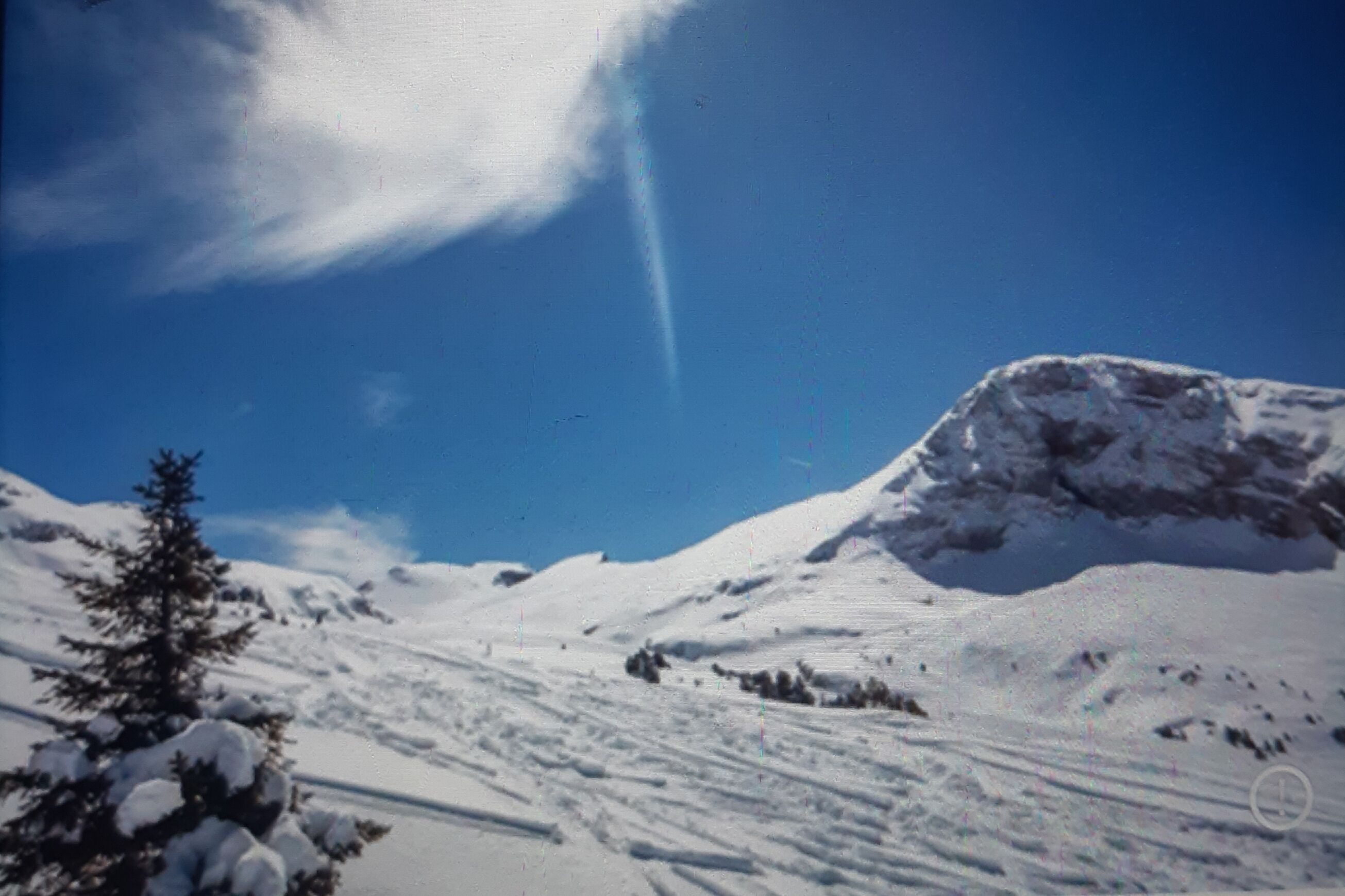 Un paysage montagneux enneigé, avec un ciel dégagé et une formation rocheuse imposante.