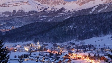 A snow-covered mountain town at dusk with illuminated buildings and a prominent church.
