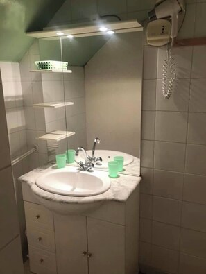 Une salle de bain avec un lavabo, un miroir et un téléphone.