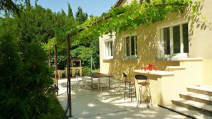 Une terrasse avec une table et des chaises, un barbecue et une fenêtre donnant sur un jardin.