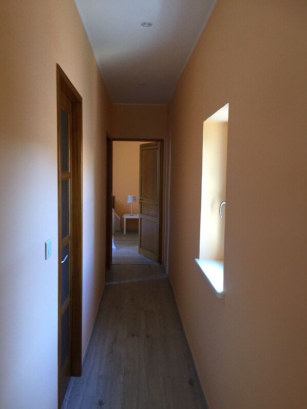 Un couloir étroit avec un plancher en bois et des murs de couleur beige.