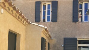 A building with a beige facade, two windows with shutters, and a door. - Charming house completely renovated with swimming pool in the heart of the village for 4 people (Capestang)