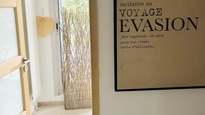A doorway leading to a room with a framed sign on the wall that reads "invitation au VOYAGE EVASION faire vagabonder son esprit partir loin, s'évasion envie d'ailleurs...". - NEW in LABAULE! Near the beach, quality flat for 4 people,garden,swimming-pool (La Baule-Escoublac)