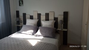A bedroom with a bed, two bedside tables with lamps, and three wall-mounted pictures.