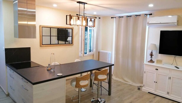 Une cuisine moderne dotée d’un îlot central, de tabourets de bar, d’un grand miroir et d’un téléviseur à écran plat.
