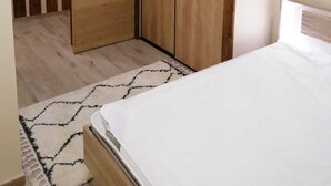 Une chambre à coucher avec un lit, une armoire en bois et un tapis à motifs.