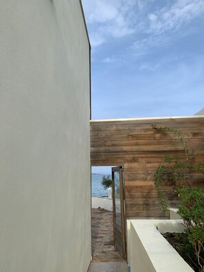 A modern architectural design with a stone pathway leading to a wooden deck overlooking a body of water. - Spacious villa in the quiet, coastal Golfe de St Tropez (Sainte-Maxime)
