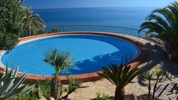 A circular swimming pool with a clear view of the ocean in the background.