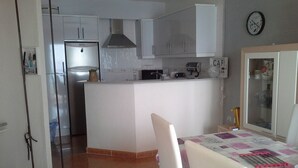 A compact kitchen with white cabinets, a stainless steel refrigerator, and a coffee maker on the counter.