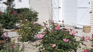 A residential property with a white garage door, a satellite dish, and a garden with pink roses. - Entire home Les Mille Roses (Nieul-sur-Mer)