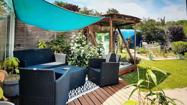 A patio with wicker furniture, a pergola, and a garden area. - Entire home Les Mille Roses (Nieul-sur-Mer)
