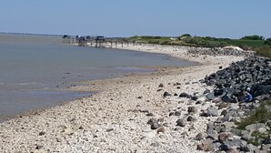 A rocky beach with a pier extending into the water. - Entire home Les Mille Roses (Nieul-sur-Mer)
