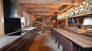 Een moderne keuken met een grote televisie, een houten plafond en een bar met zitplaatsen.