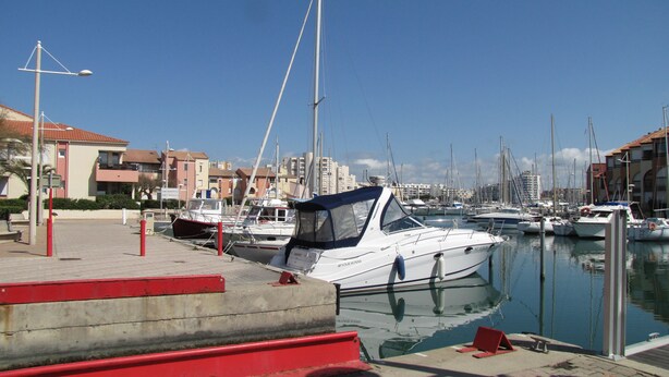 A marina with several boats docked, a clear sky, and buildings in the background. - Panoramic sea and pond view not overlooked. (Mauguio)