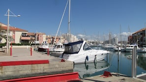 Boats docked in a tranquil marina adjacent to Mediterranean-style buildings.