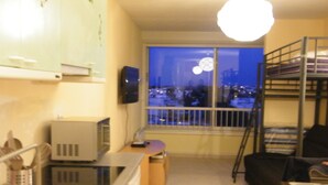 A compact living space with a kitchenette, a bunk bed, and a window overlooking a cityscape at night. - Panoramic sea and pond view not overlooked. (Mauguio)
