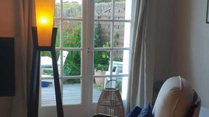 A room with a large window, a floor lamp, a chair with cushions, and a small table. - House near paths and the Ria d'Etel 6 PERS. (Plouhinec)