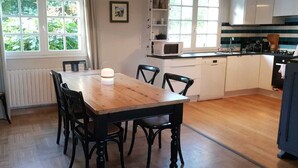 A cozy kitchen with a wooden table and chairs, a microwave, and a coffee maker. - House near paths and the Ria d'Etel 6 PERS. (Plouhinec)