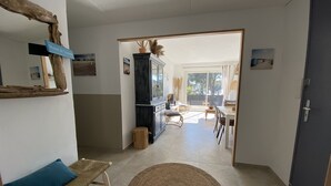 A spacious living area with a sofa, a round rug, and a dining table. A cabinet and a mirror are also visible. - 30m from the beach, air-conditioned house, sea view, enclosed garden, ideal for families (Saint-Raphaël)