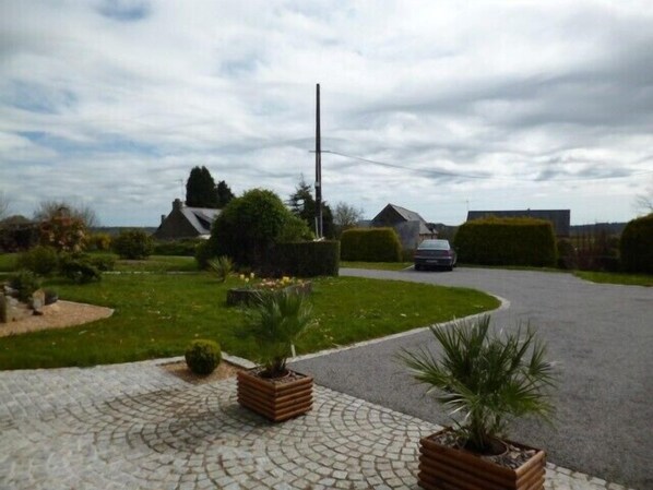 A residential street with houses, a car, and potted plants on the sidewalk. - Quiet gîte on the outskirts of Quimper, rated 3*, 3 bedrooms, sleeps 6, fully equipped, (Quimper)