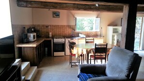 Una cocina compacta con comedor, televisor y ventana.