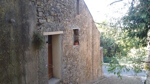 Un edificio de piedra con una estrecha entrada empedrada y una ventana pequeña.
