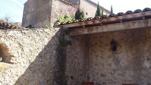 Un edificio de piedra con techo de tejas, un banco de madera y una mesa con sillas.